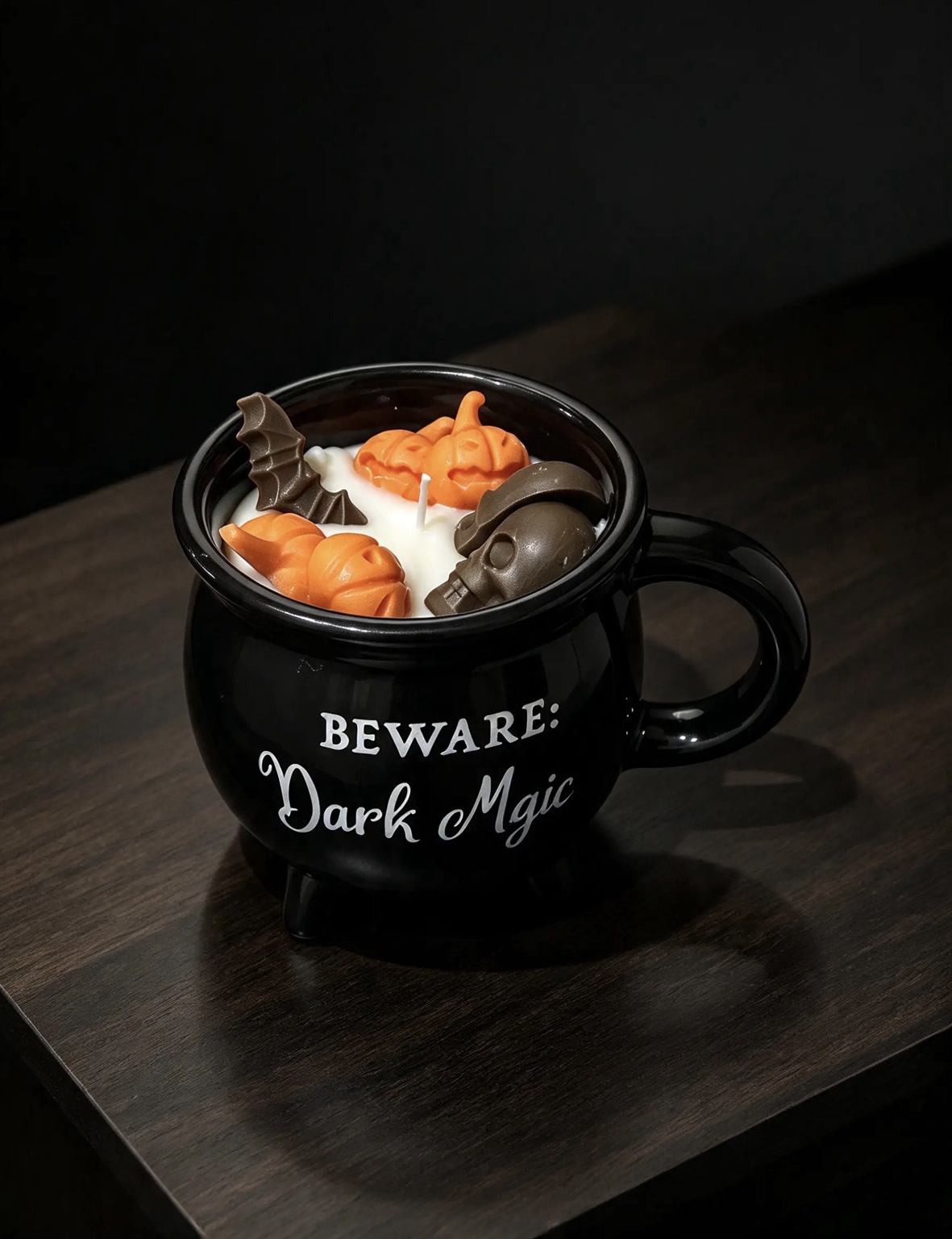 Candela Dark Magic in una tazza nera, decorata con zucche e pipistrello di cera